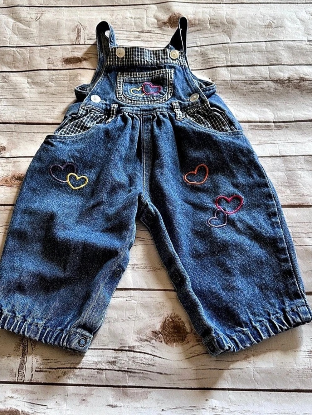 Blue denim overalls with embroidered hearts in multiple colors